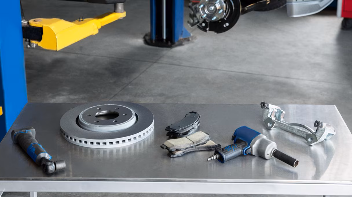 Ford brake rotor, brake pads, and repair tools laid out on service shop table