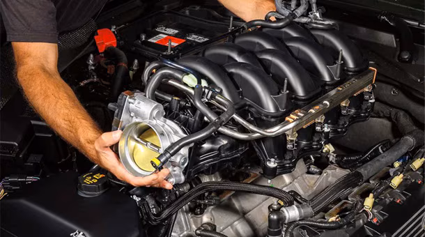 Technician's hands installing throttle body on Ford Mustang engine