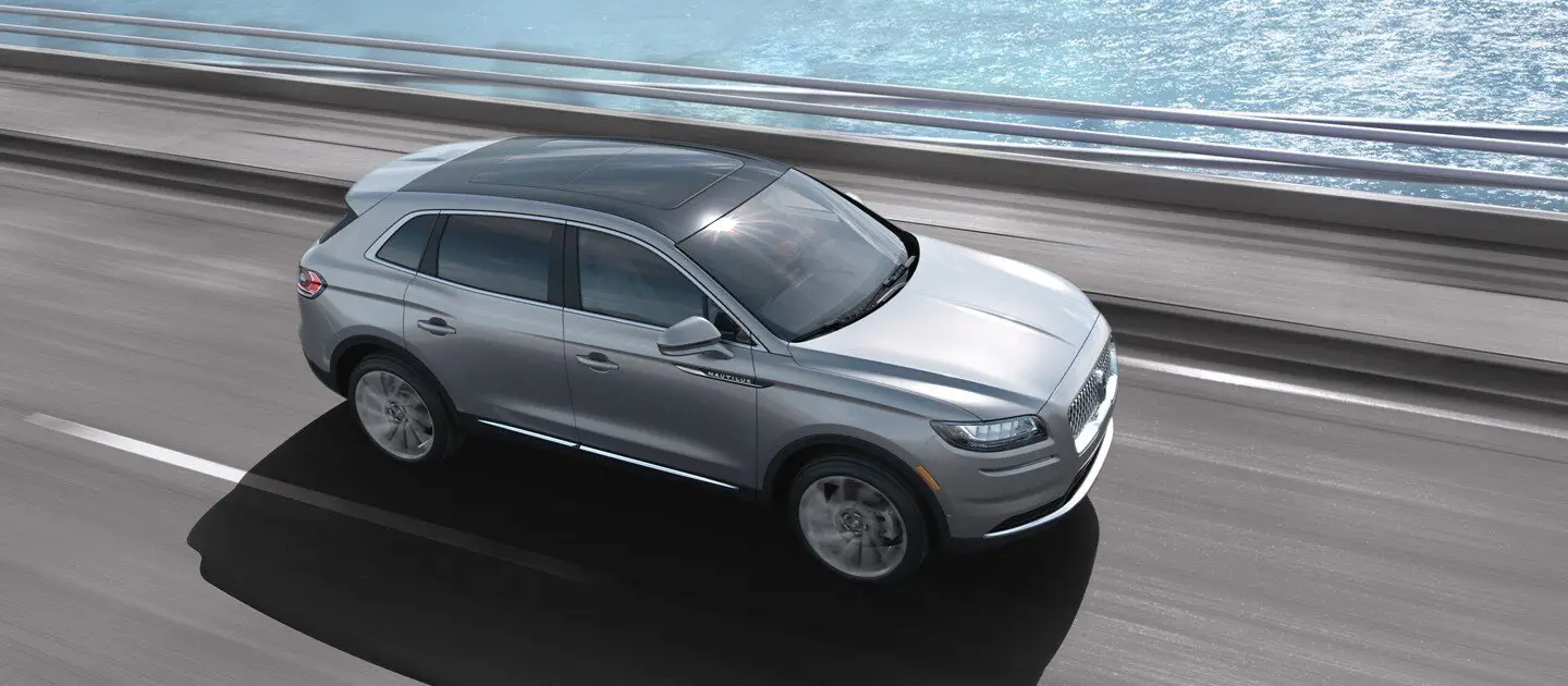 Aerial view of silver Lincoln Nautilus SUV driving over waterside bridge