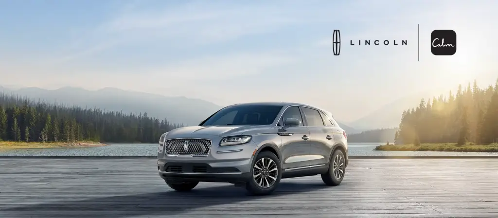 Silver Lincoln Nautilus SUV on lakeside dock with Lincoln and Calm app logos