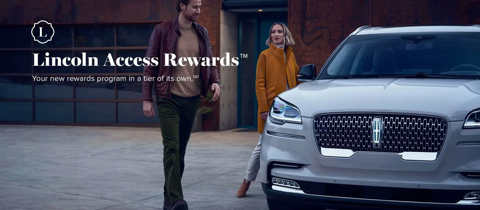 Couple walking toward white Lincoln SUV with Lincoln Access Rewards program branding