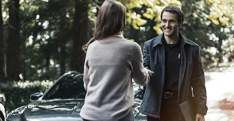 Lincoln client advisor greeting customer beside vehicle in wooded setting