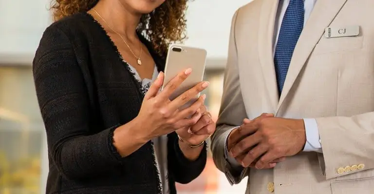 Close-up of customer using smartphone next to Lincoln concierge in suit