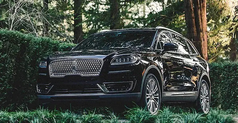 Black Lincoln Nautilus SUV parked among trees and greenery