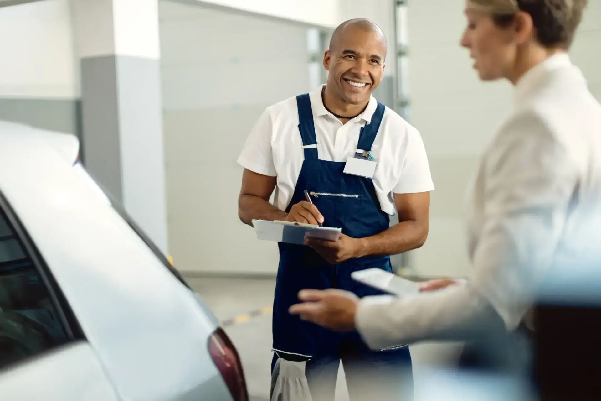 Happy black mechanic taking notes while talking customer auto repair shop scaled 1.webp