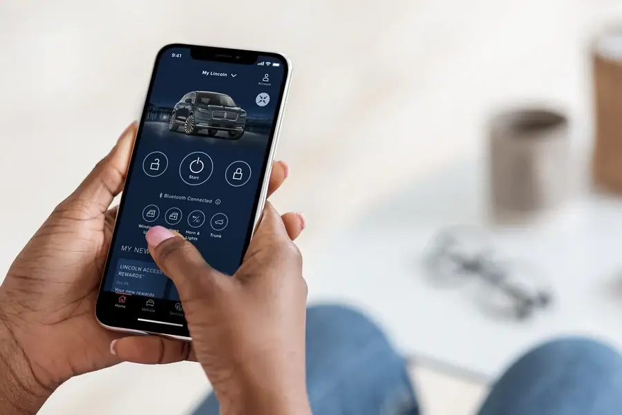 Hands holding smartphone with Lincoln Way app vehicle control screen
