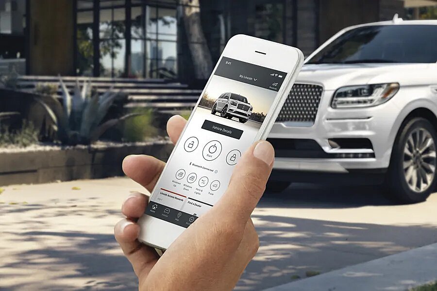 Hand holding smartphone displaying Lincoln Way app with remote start and vehicle details