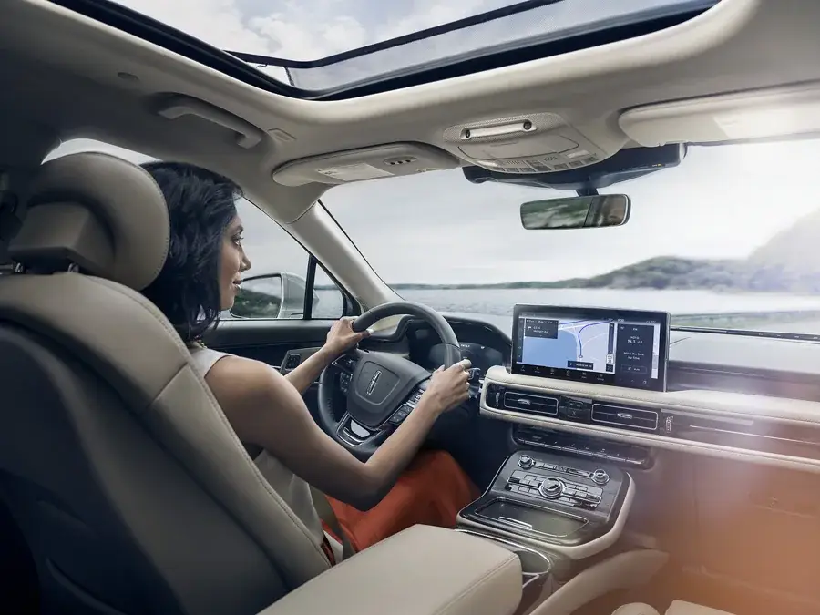 Woman driving Lincoln SUV with panoramic sunroof and center touchscreen navigation